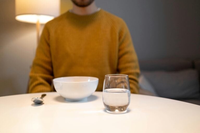 Man sitting at a table with an empty bowl and a glass of water.