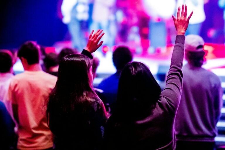 People at a church service - some have their hands in the air.