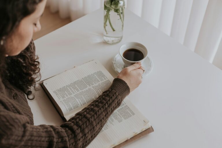 Woman reading her bible with a cup of coffee.