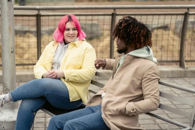 Two people talking on a park bench.