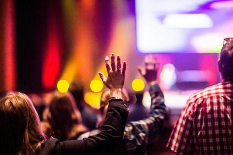 Looking from the back of a church seeing lots of hands raised in worship.